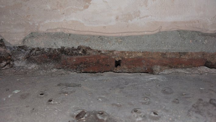 An image showing the bottoms of the exposed bricks internally, above the small 2cm gap is internal cement render. The lime mortar between some of the bricks is badly eroded.